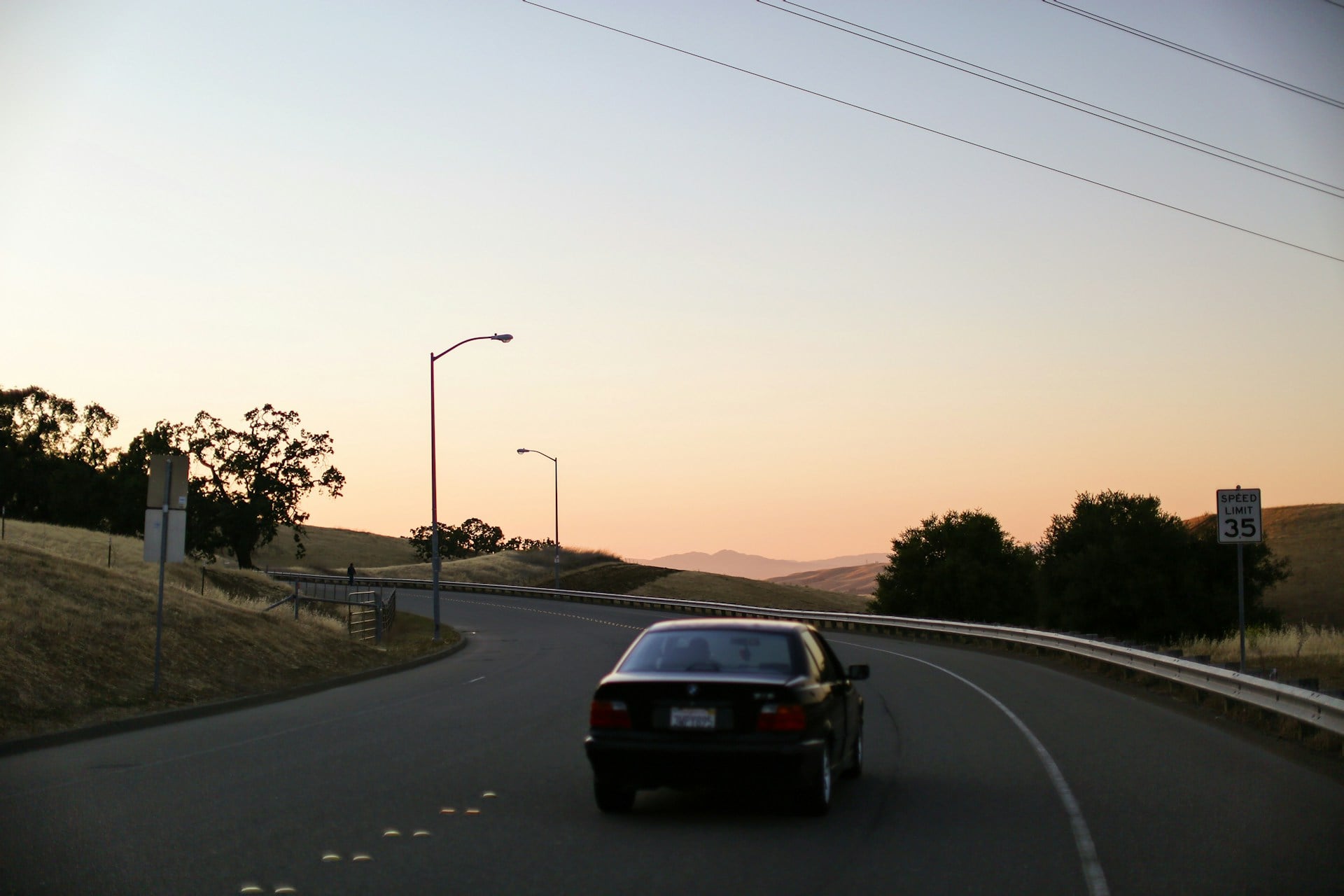 Car driving through rolling hills at dusk